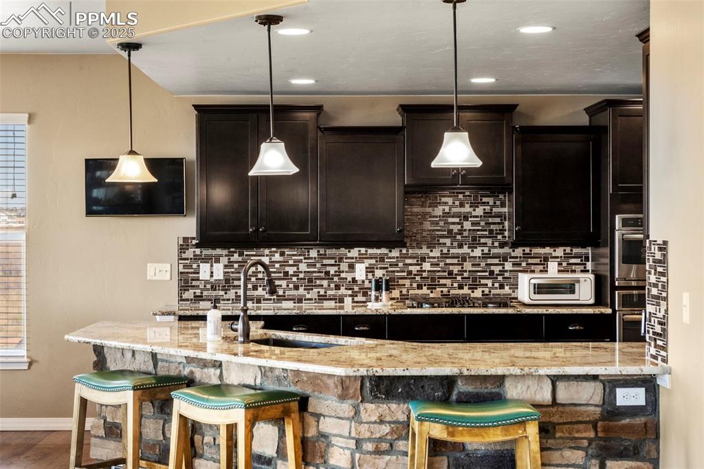 Image 17 of 41: Kitchen with a kitchen breakfast bar, tasteful backsplash, dark brown cabin