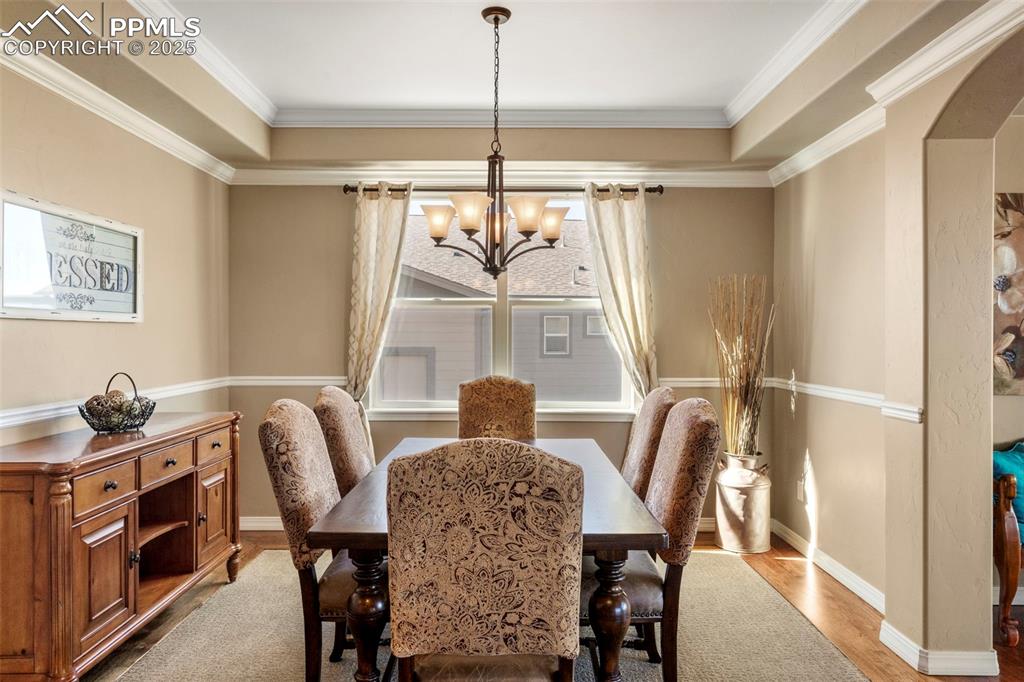 Image 19 of 41: Dining area featuring wood finished floors, arched walkways, crown molding,
