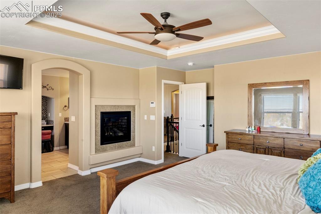 Image 23 of 41: Bedroom featuring a tray ceiling, carpet floors, ceiling fan, crown molding