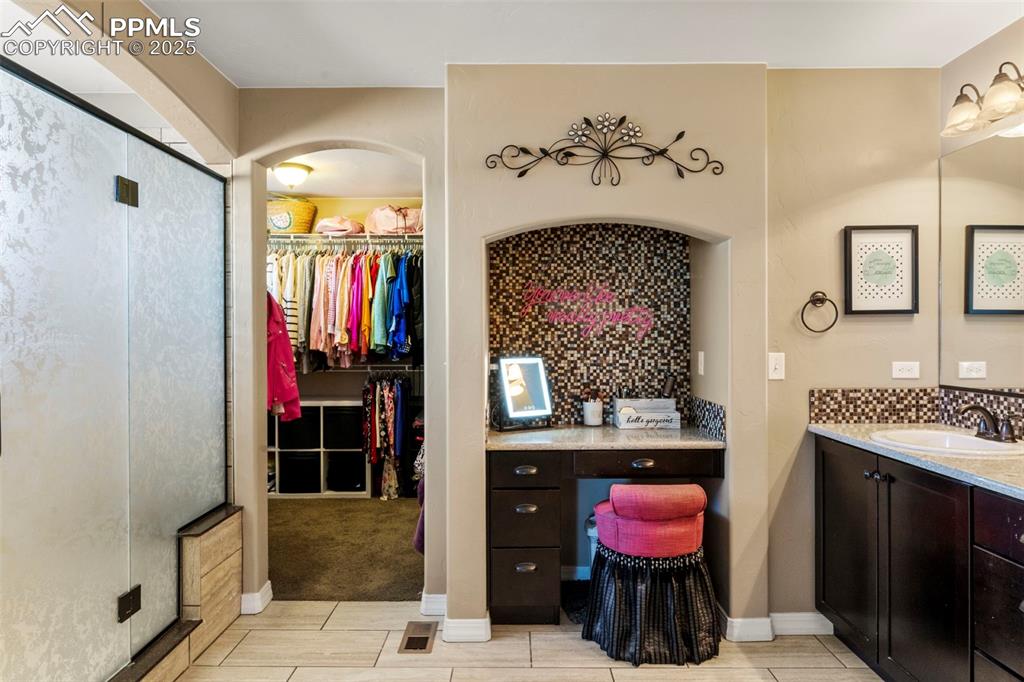 Image 24 of 41: Bathroom featuring vanity, a walk in closet, a shower stall