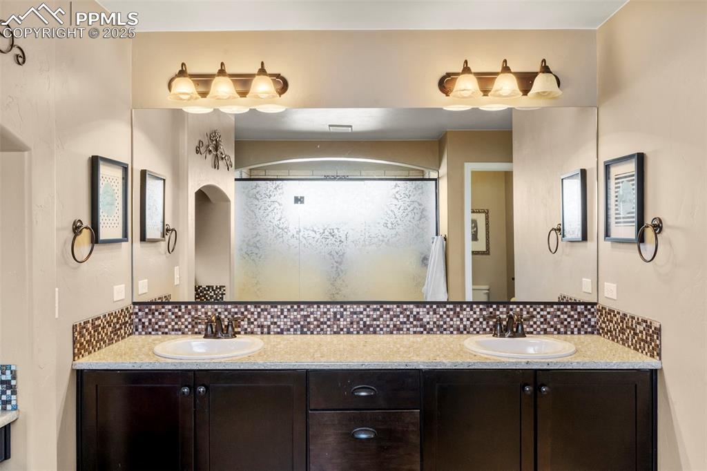 Image 25 of 41: Bathroom featuring tasteful backsplash, double vanity, and a shower stall