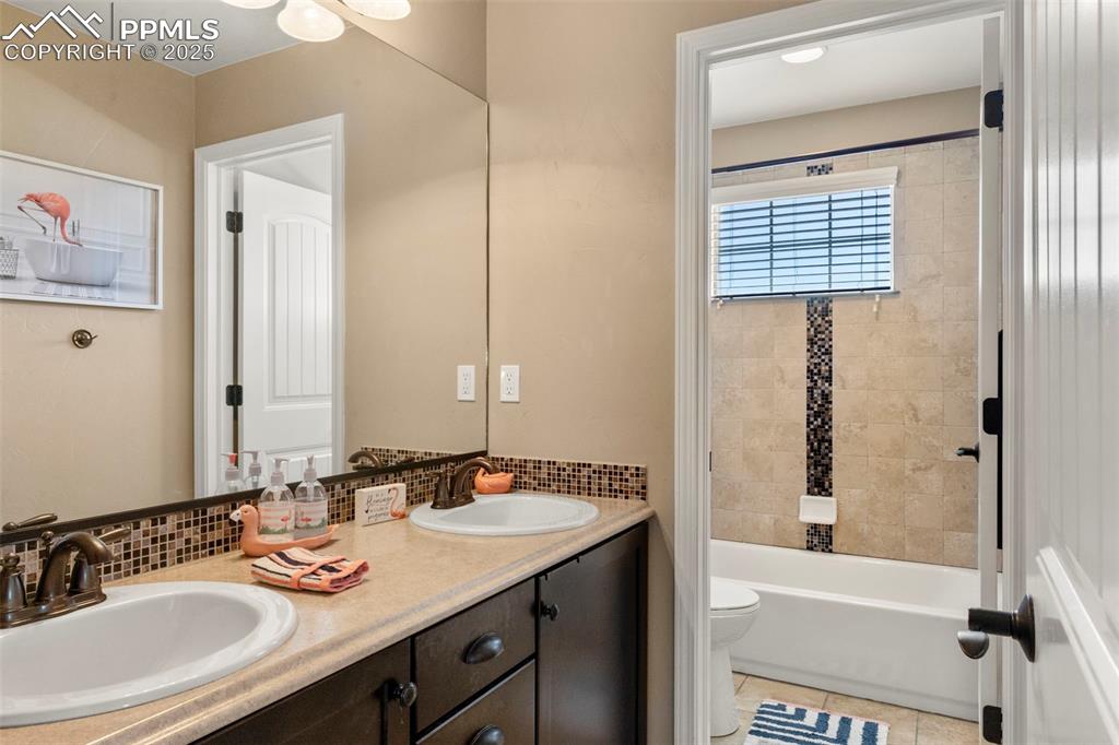 Image 30 of 41: upper secondary bathroom featuring double vanity, light tile combination, a
