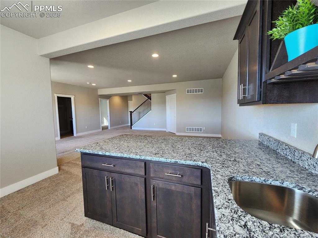 Image 30 of 50: wet bar featuring granite counterops, a sink, and ample upper and lower cab