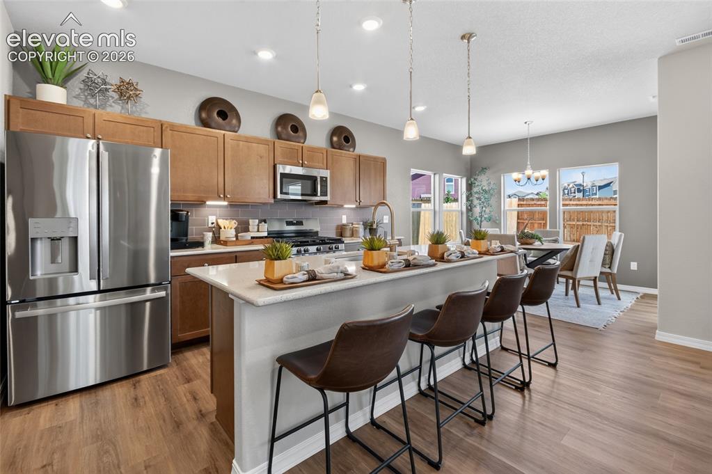 Image 11 of 45: Open-concept living area featuring wood-finish flooring, recessed lighting,