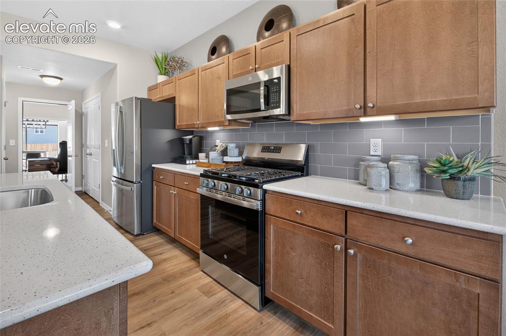 Image 16 of 45: Kitchen island with light-toned countertop, stainless steel microwave, grey