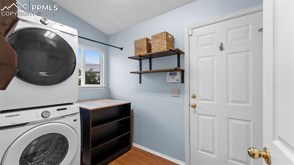 Image 14 of 33: Laundry room with light wood-style flooring, stacked washer and clothes dry