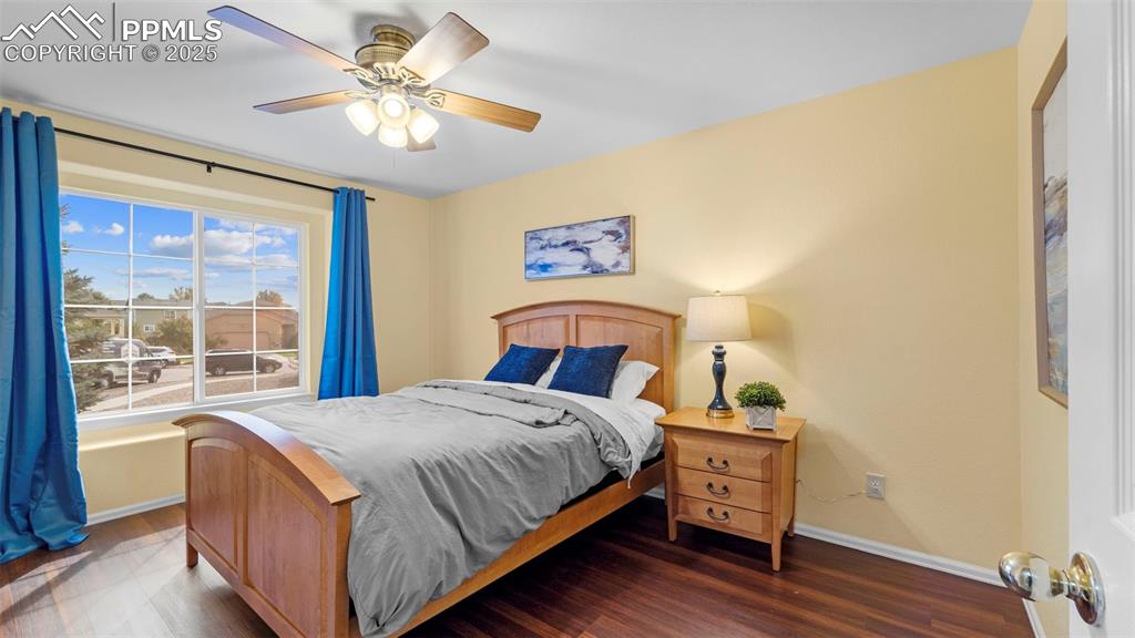 Image 17 of 33: Bedroom with wood finished floors and a ceiling fan