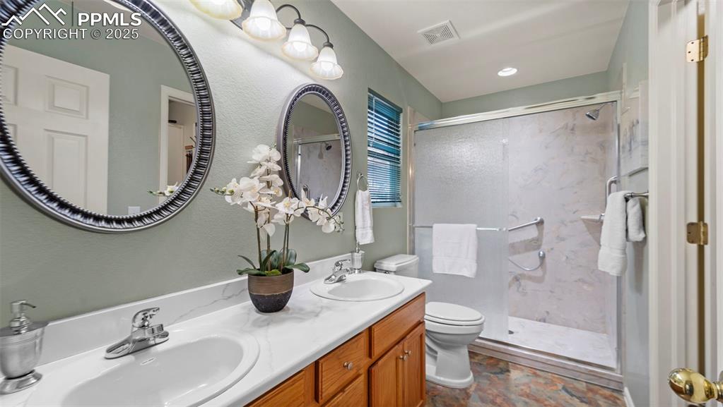 Image 18 of 33: Full bath featuring a marble finish shower, double vanity, and a textured w