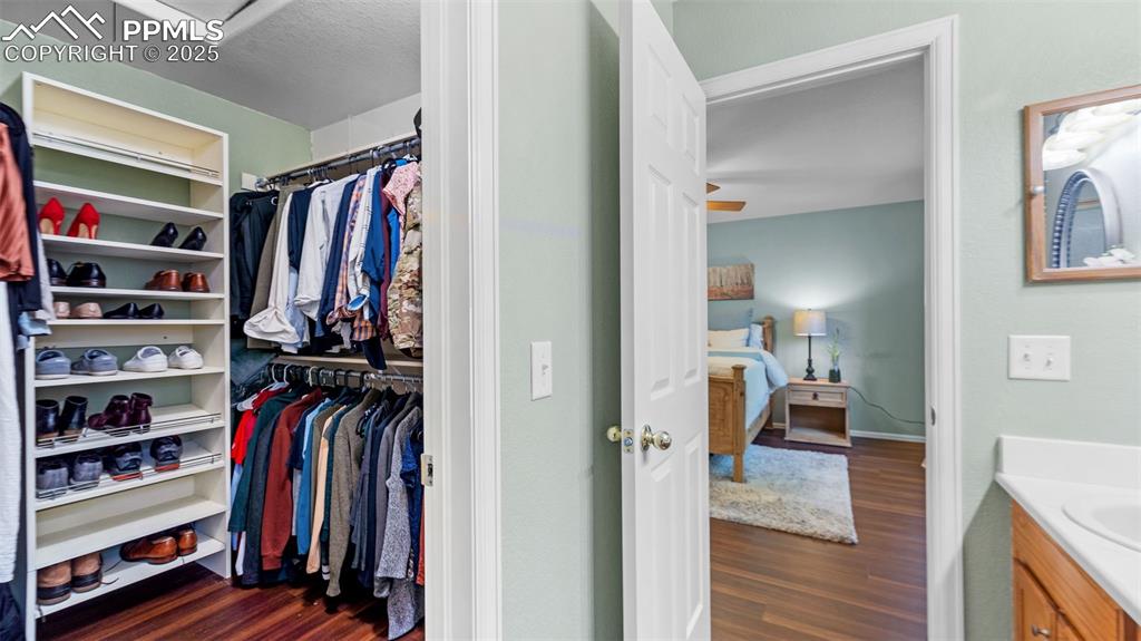Image 19 of 33: Walk in closet with dark wood-type flooring
