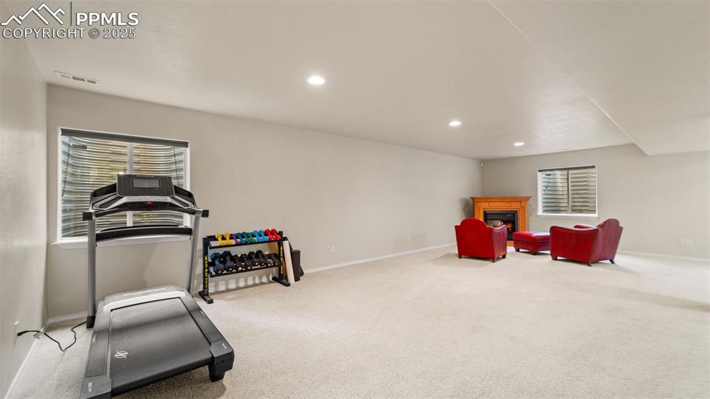 Image 22 of 33: Living area with a fireplace, light colored carpet, recessed lighting, and 