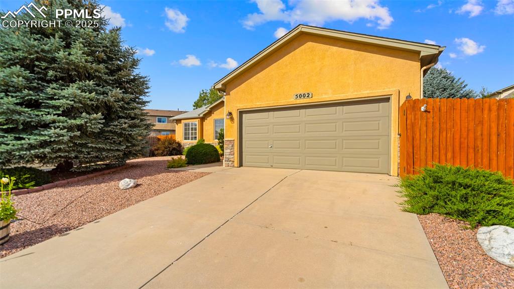 Image 3 of 33: View of front of property with stucco siding, driveway, a garage, and stone