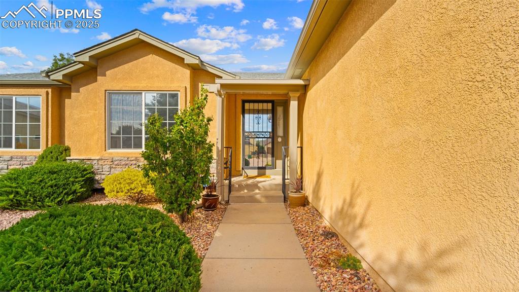 Image 5 of 33: Doorway to property featuring stucco siding and stone siding
