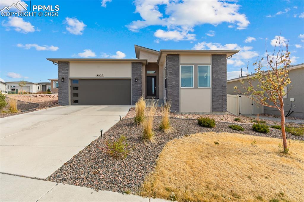 Caption: Contemporary stucco and stone-veneer exterior featuring a prominent two-car garage with frosted glas