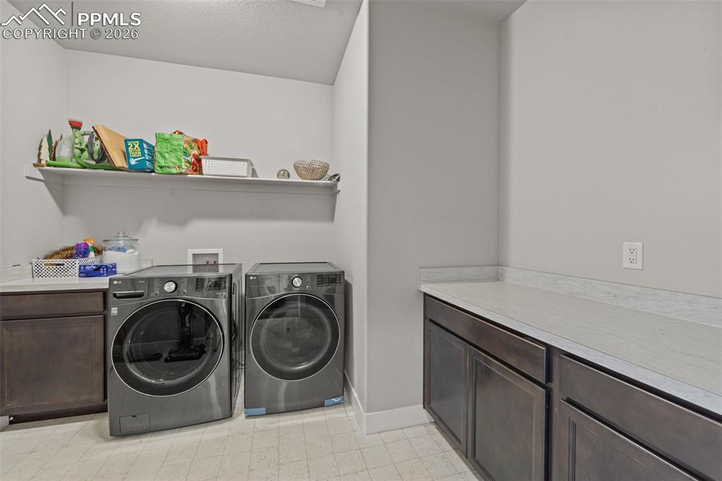 Image 10 of 49: Dedicated laundry area featuring dark wood cabinetry, light-toned counterto