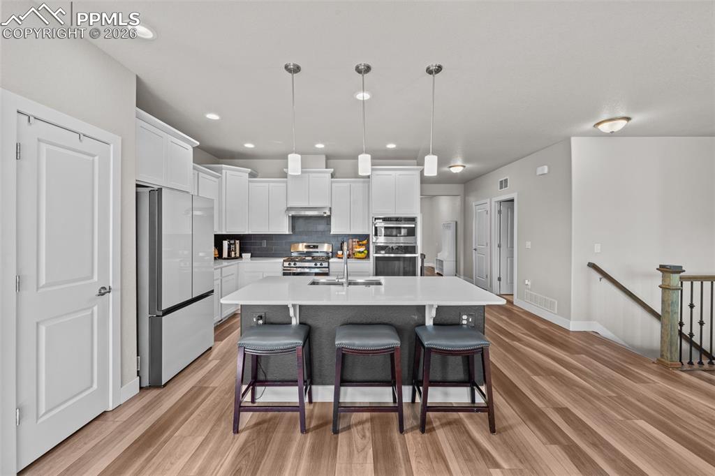 Image 14 of 49: Open-concept kitchen featuring an oversized island with seating, pendant li