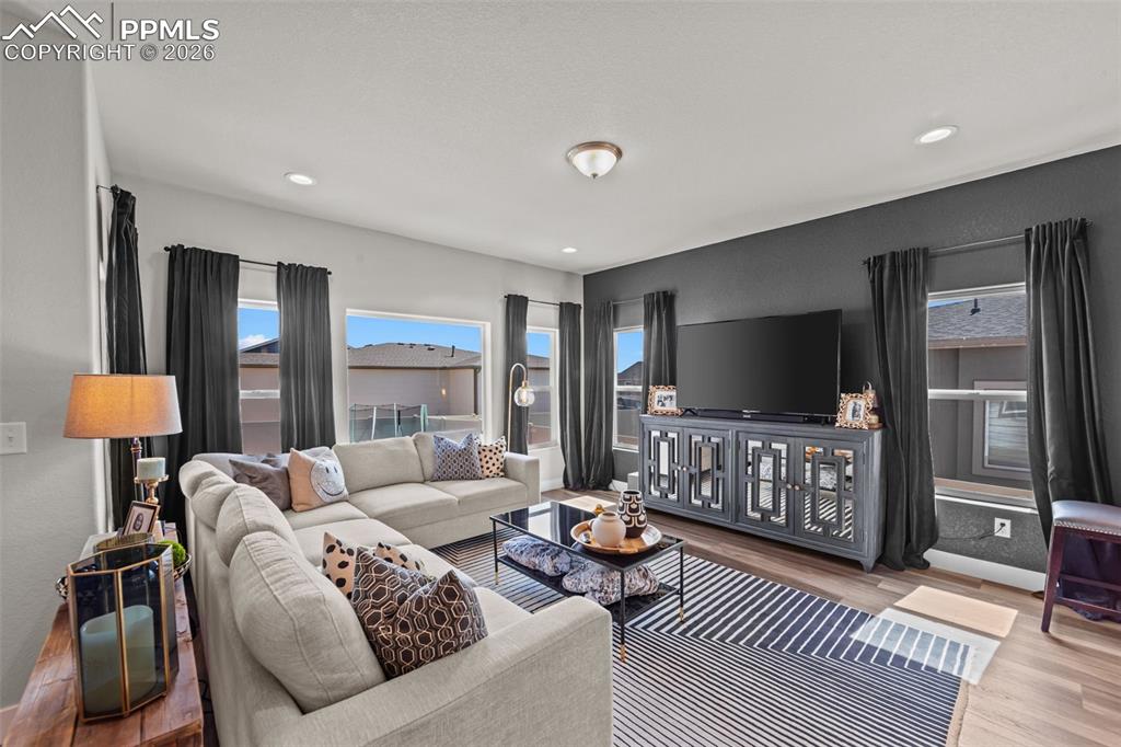 Image 17 of 49: Living area featuring wood-finish flooring, recessed lighting, and large wi