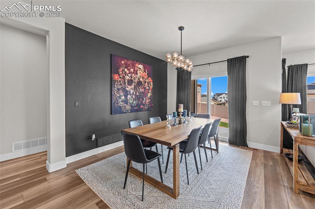 Image 20 of 49: Dining area featuring a dark accent wall, wood-finish flooring, and a moder