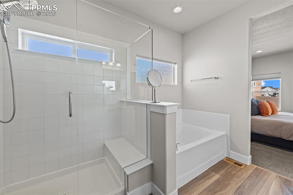 Image 24 of 49: Walk-in shower with clear glass enclosure and integrated bench seating