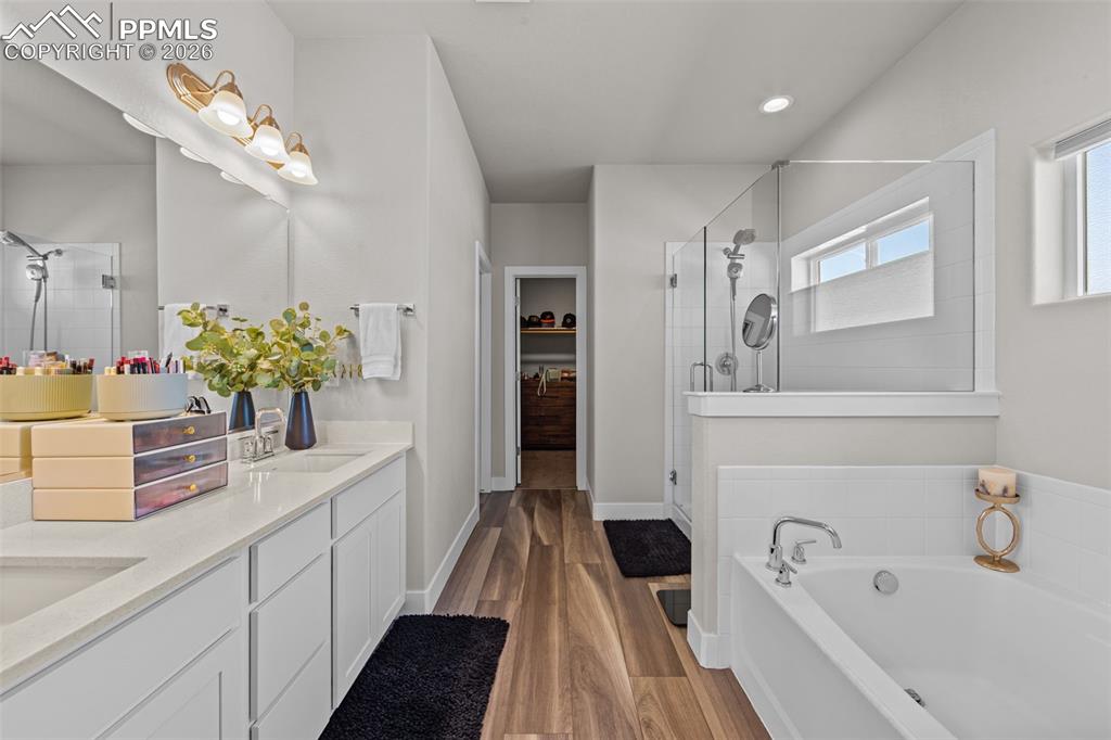 Image 25 of 49: Bathroom featuring a double vanity with stone countertops, wood-finish floo