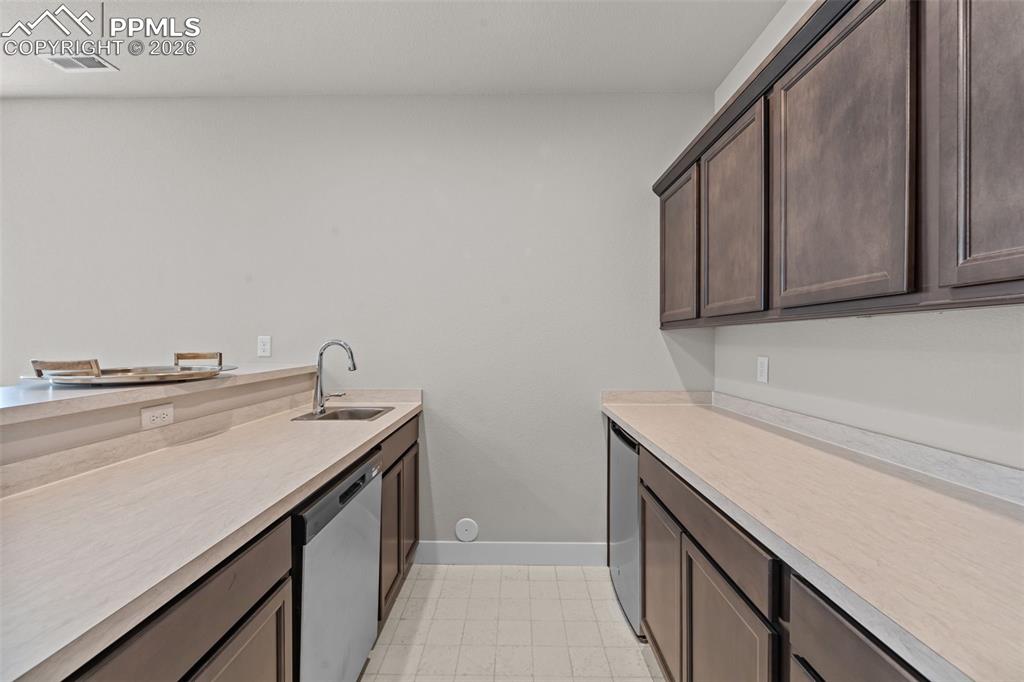 Image 29 of 49: Utility area featuring a stainless steel sink, gooseneck faucet, light-tone