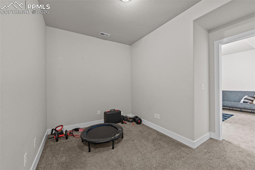 Image 32 of 49: Carpeted room with light gray walls, white baseboards, and a doorway leadin