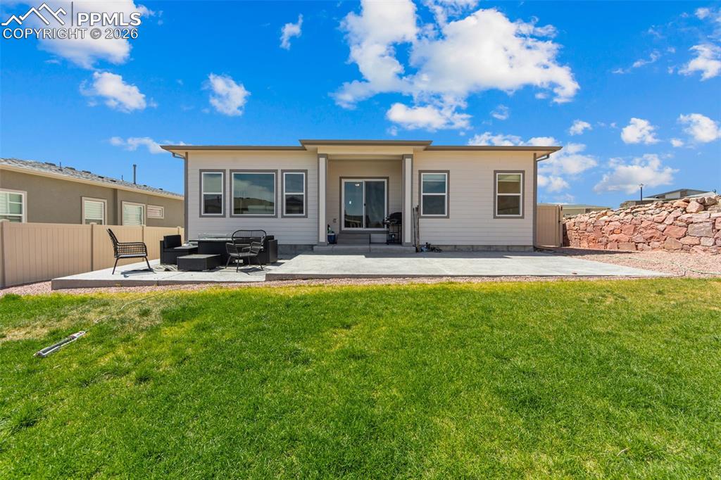 Image 34 of 49: Expansive backyard featuring a manicured lawn, a large concrete patio, and