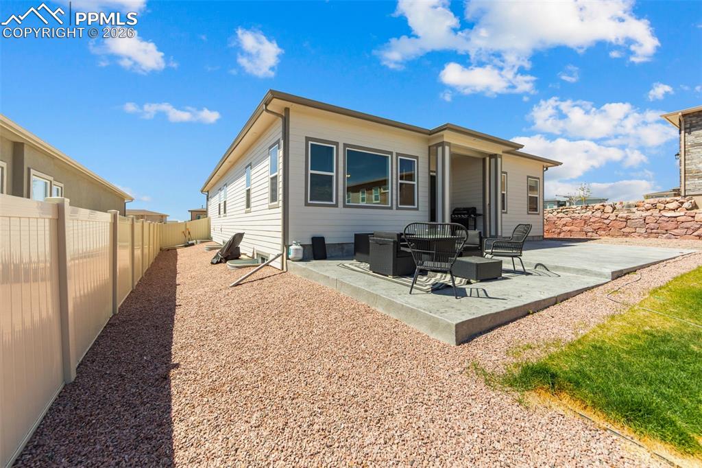 Image 36 of 49: Rear exterior featuring a concrete patio, covered porch, and a gravel-cover