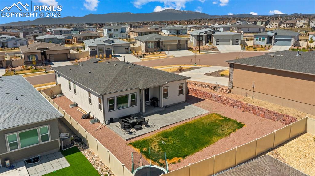 Image 43 of 49: Rear exterior featuring a concrete patio, partial fenced yard with artifici