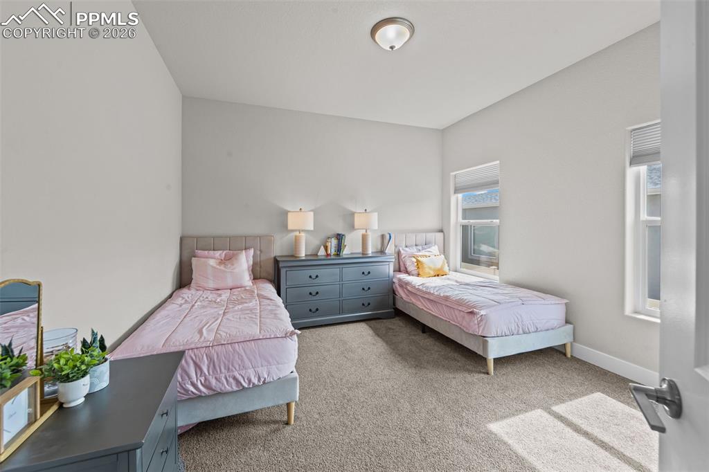 Image 9 of 49: Carpeted room with light neutral walls, two window openings with blinds, an