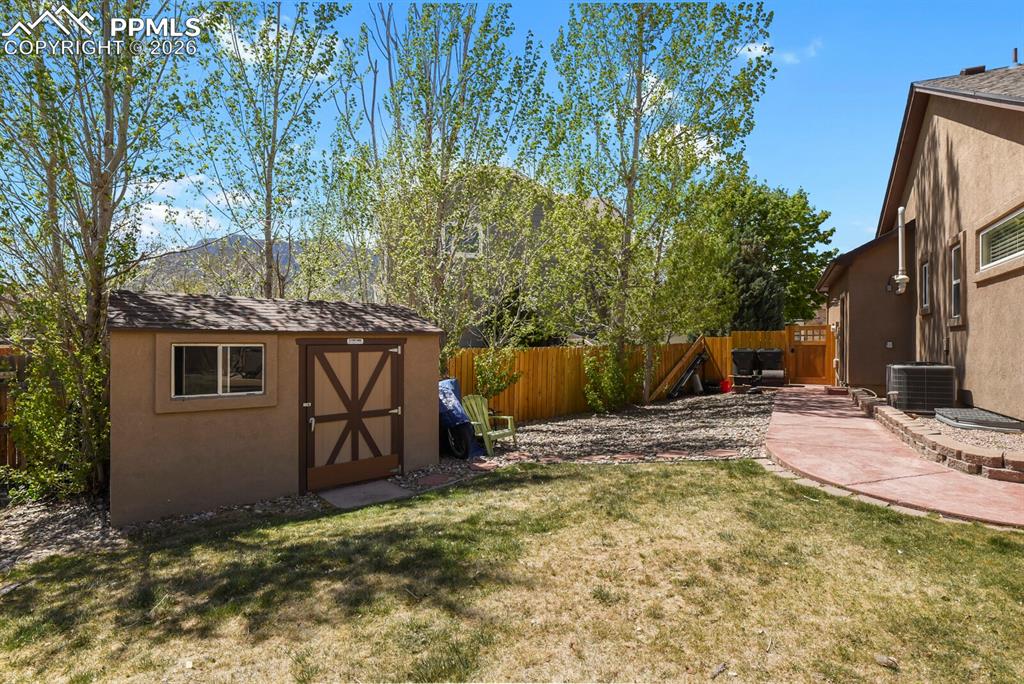 Image 27 of 34: Side yard with matching stucco shed