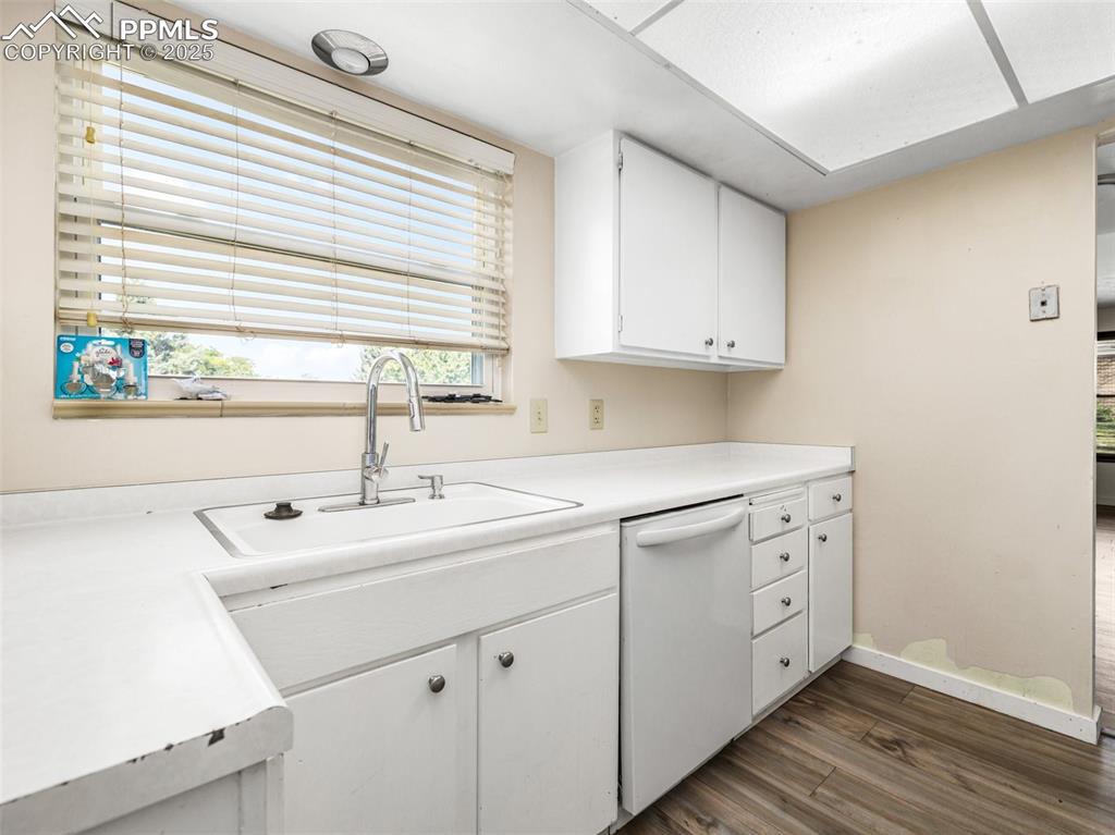 Image 11 of 28: Kitchen with white cabinets, light countertops, dark wood finished floors,