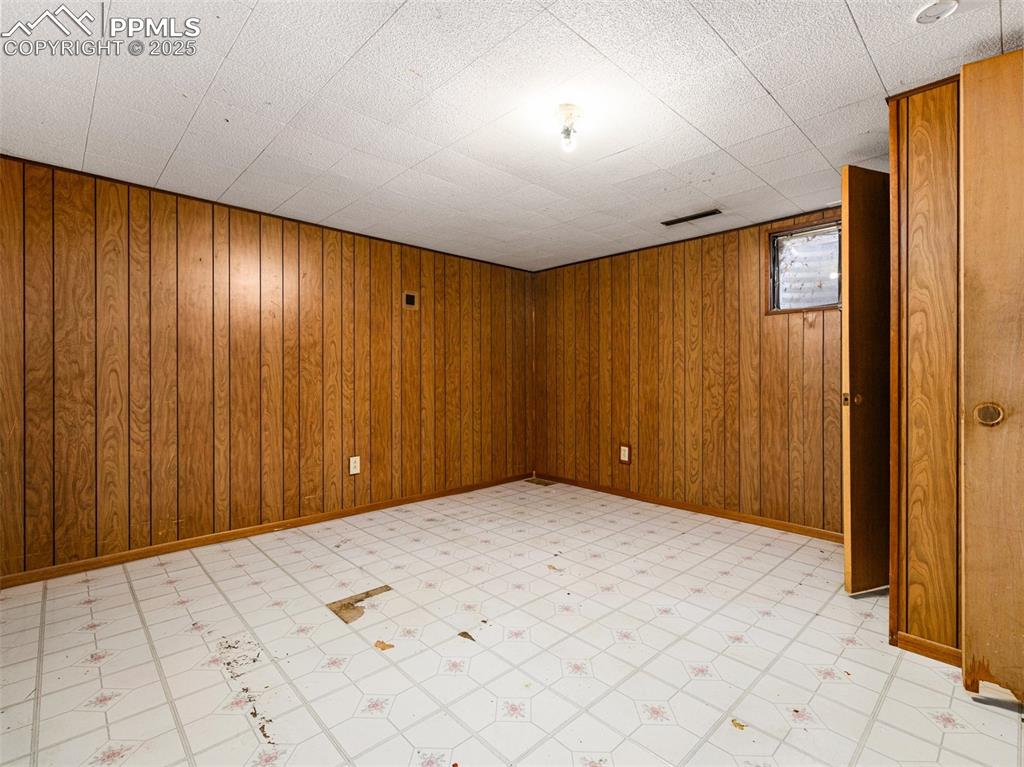 Image 17 of 28: Basement with wooden walls and light flooring