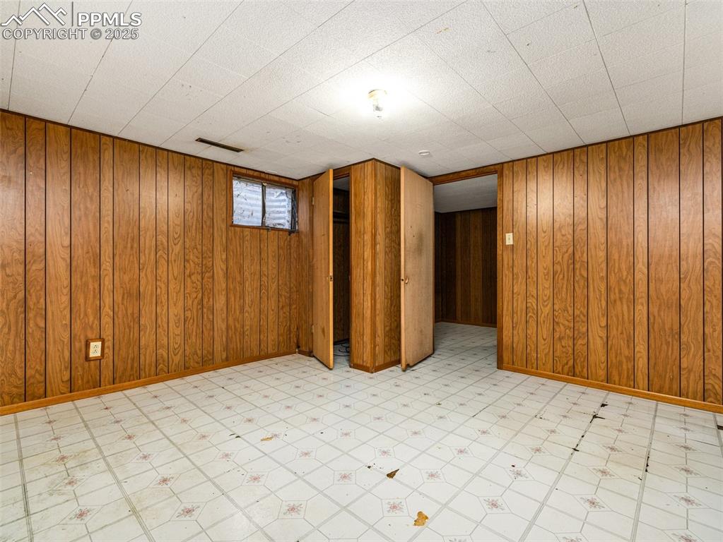 Image 18 of 28: Basement with light floors and wooden walls