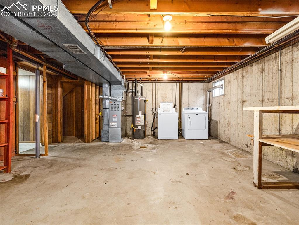 Image 20 of 28: Below grade area featuring heating unit, water heater, and washing machine