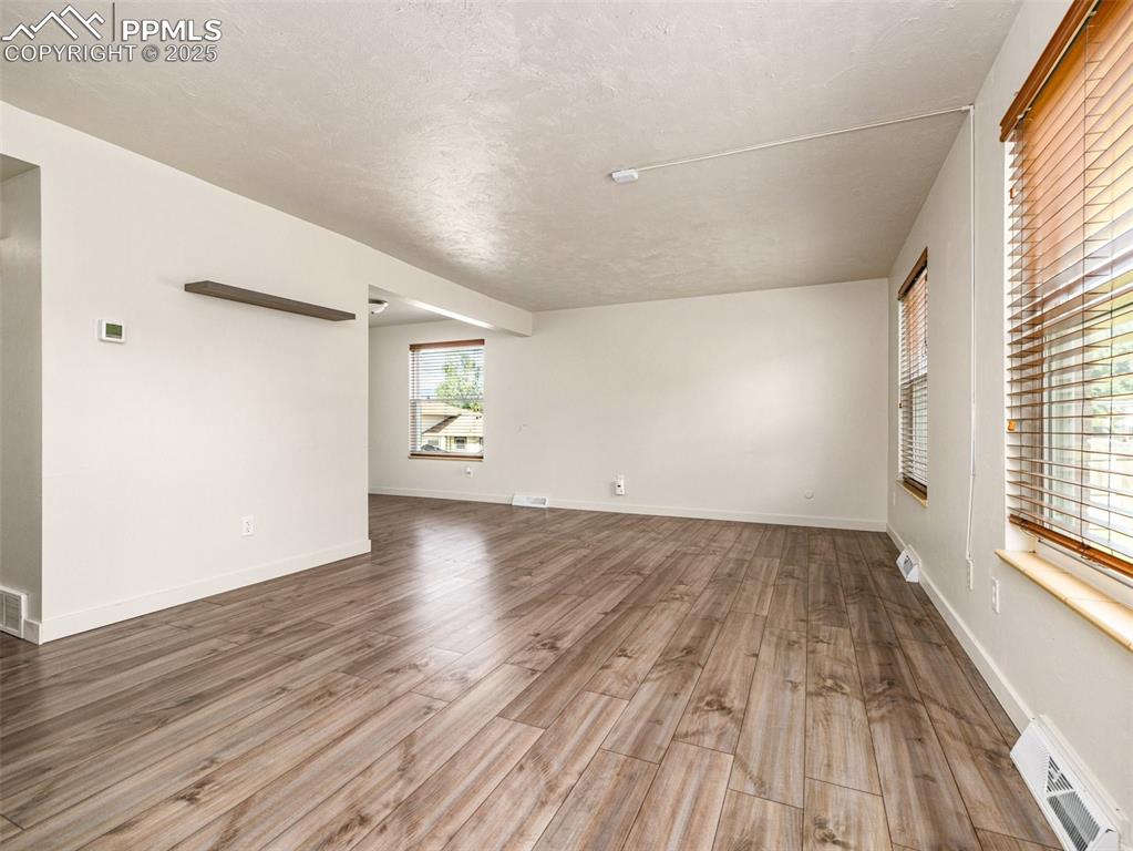 Image 5 of 28: Empty room featuring light wood-type flooring and a textured ceiling