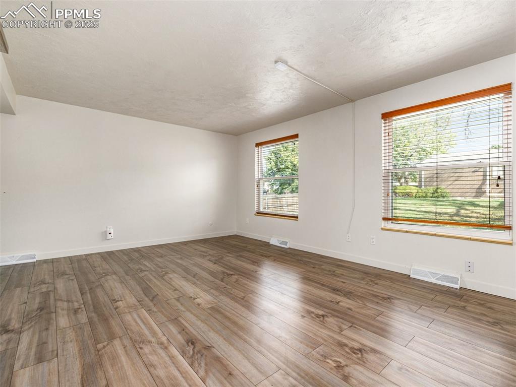 Image 6 of 28: Spare room with wood finished floors and a textured ceiling