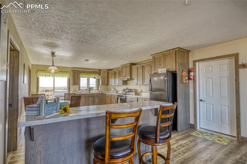 Image 13 of 50: Kitchen featuring wood finish cabinets, a kitchen breakfast bar, light wood
