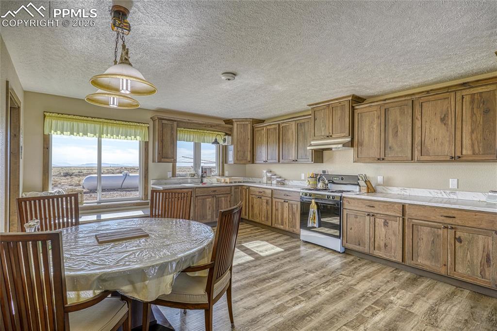 Image 16 of 50: Kitchen featuring wood finish cabinets, white range, light countertops, lig