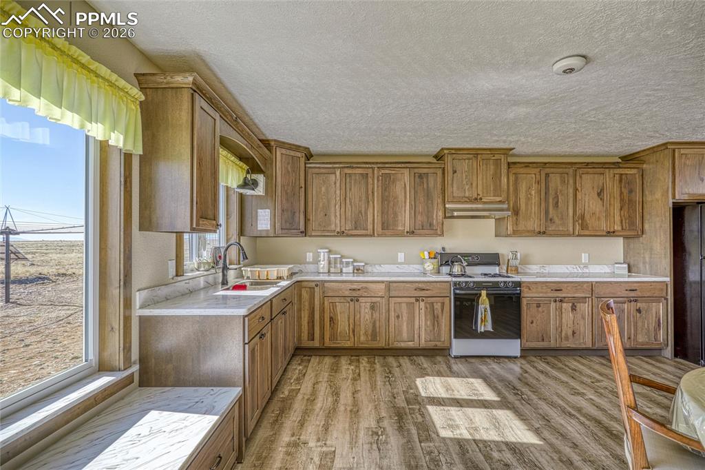 Image 17 of 50: Kitchen featuring wood finish cabinetry, range with gas cooktop, light coun