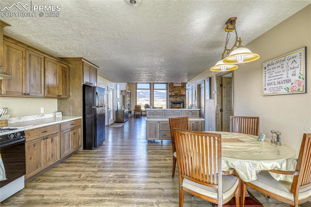 Image 18 of 50: Dining area with light wood finished floors, a textured ceiling, and a text