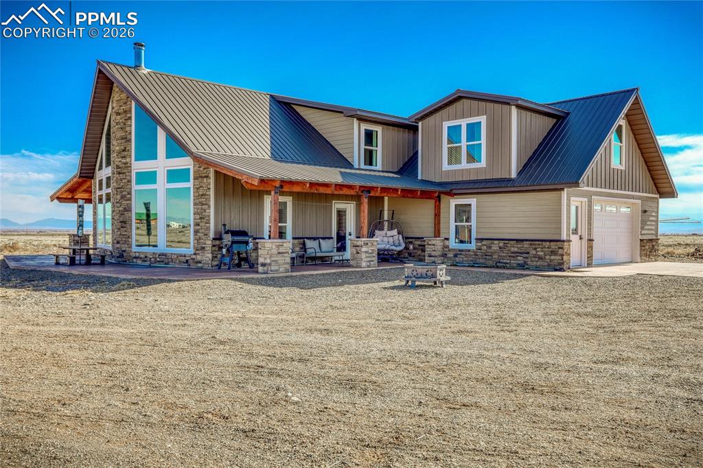 Image 2 of 50: View of front of house featuring stone siding, a metal roof, driveway, and