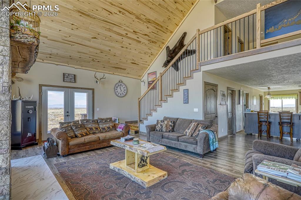 Image 28 of 50: Living room with french doors, wood finished floors, and a vaulted wood cei