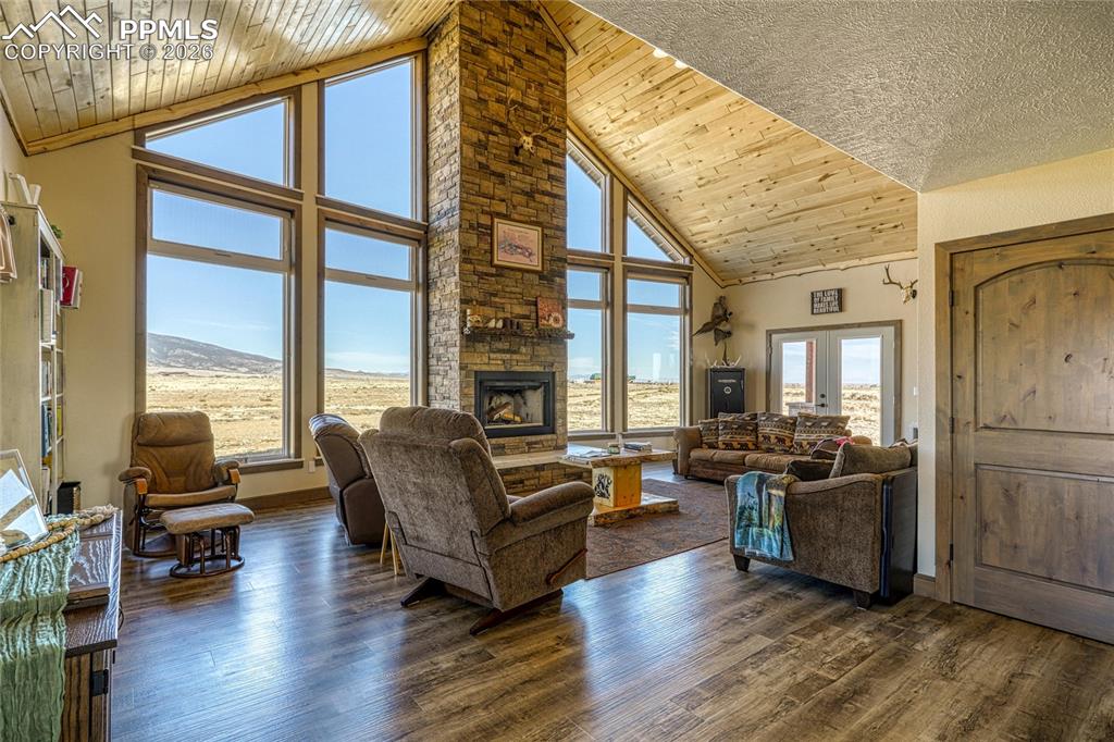 Image 8 of 50: Living room featuring a high wood ceiling, dark wood-style floors, a firepl