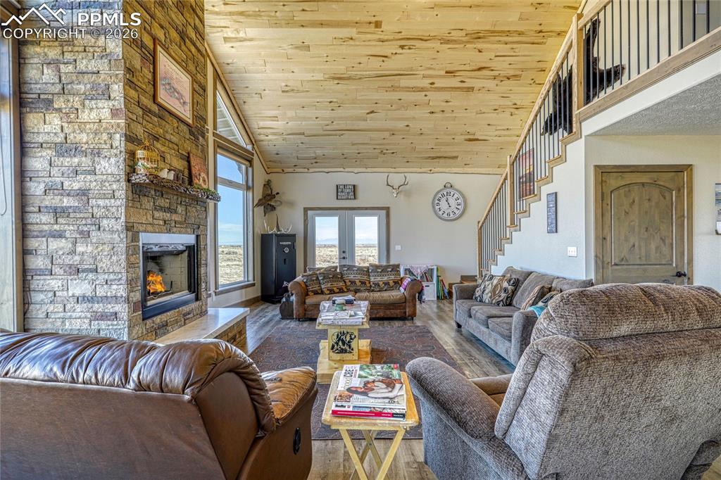 Image 9 of 50: Living area with a stone fireplace, a vaulted wooden ceiling, wood finished