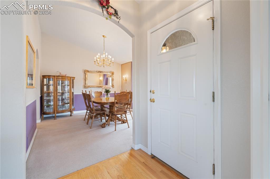 Image 11 of 49: Foyer with lofted ceiling, light hardwood / wood-style flooring, and a chan