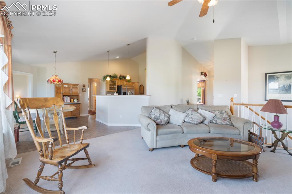 Image 17 of 49: Carpeted living room featuring ceiling fan and vaulted ceiling