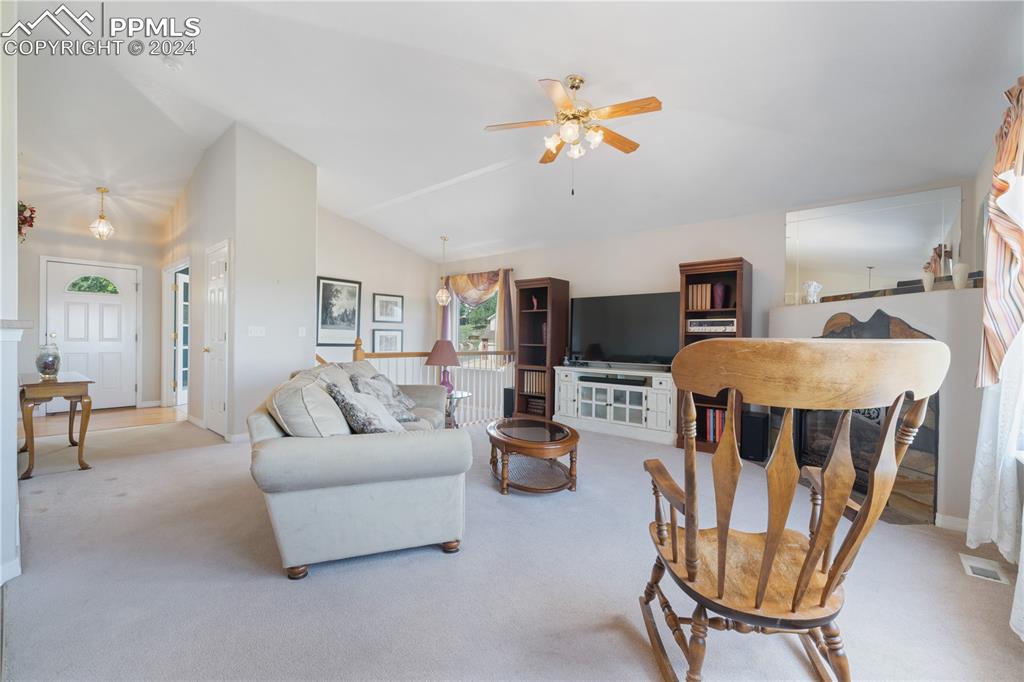 Image 18 of 49: Living room featuring high vaulted ceiling, ceiling fan, and light colored 