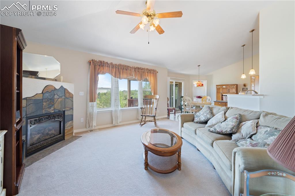 Image 19 of 49: Living room featuring carpet flooring, vaulted ceiling, and ceiling fan