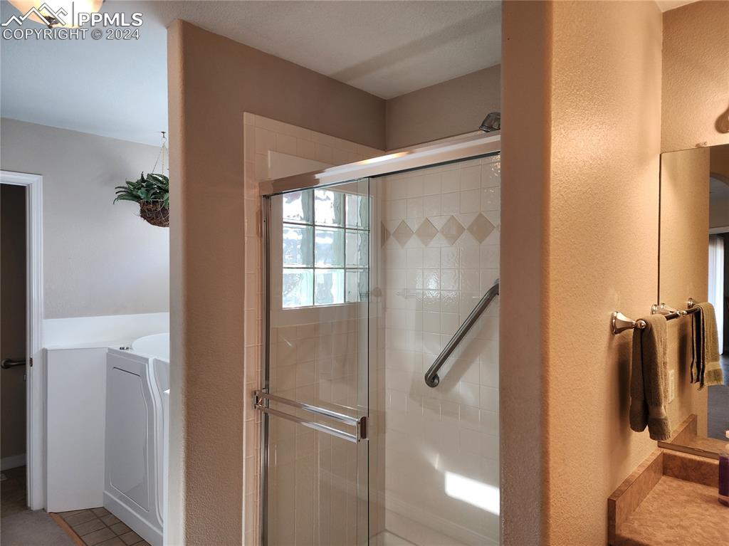 Image 25 of 49: Bathroom featuring tile patterned flooring, washing machine and dryer, and 
