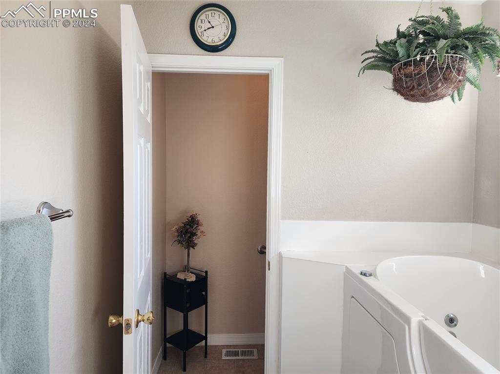 Image 26 of 49: Bathroom featuring a washtub and tile patterned flooring